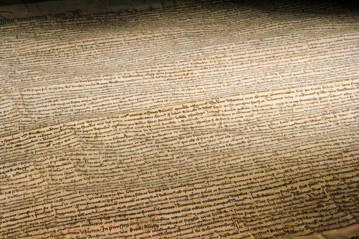 A close-up of an aged manuscript with dense handwritten Latin script, slightly creased and illuminated by soft light.