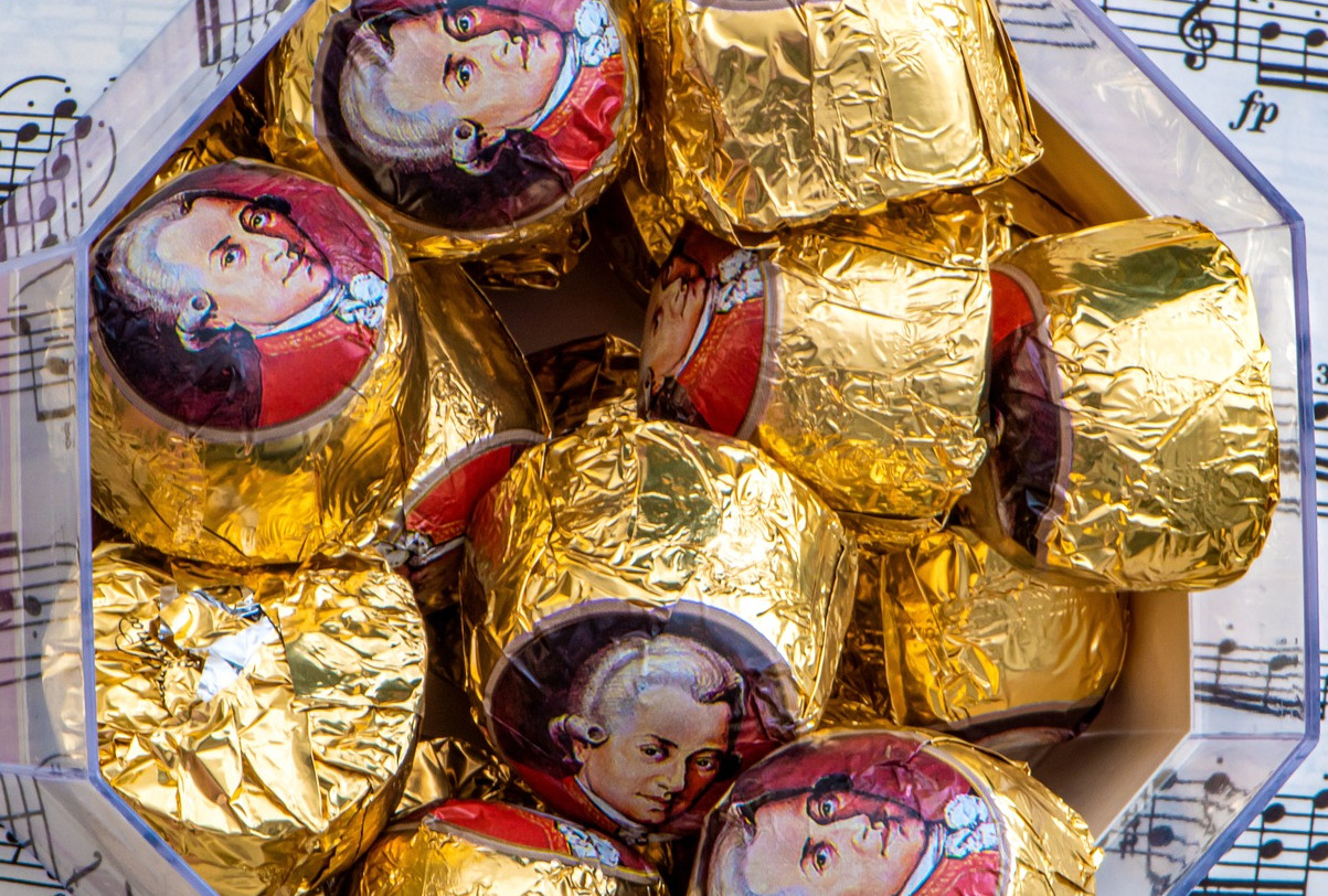 Bowl containing chocolates wrapped in foil showing Mozart portrait; some sheet music in background