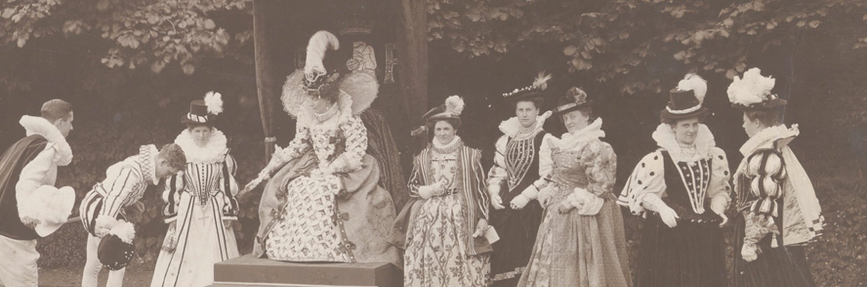 A black and white photo showing a group of women and two men donning period costumes.