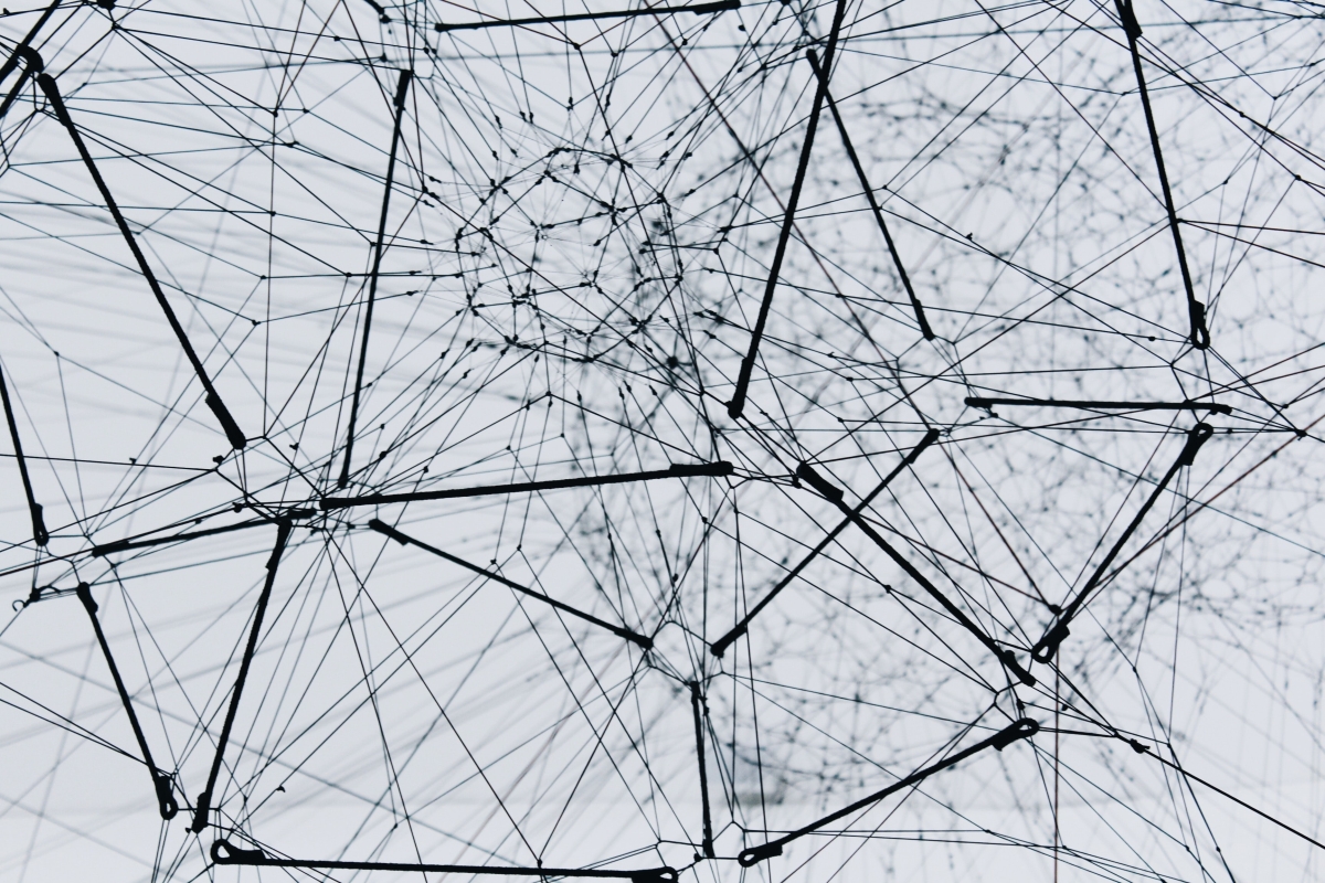 3D artwork of dark thread and straight dark wire material forming a network of nodes interconnected across space. 
